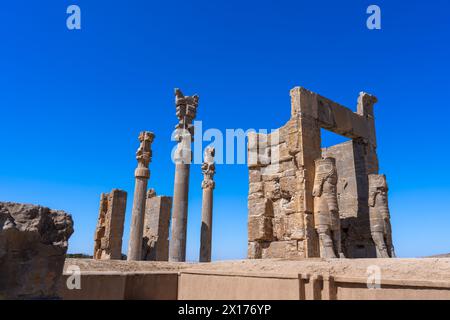 Imponenti statue di Lamassu si ergono alte, gettando intricate ombre tra le antiche rovine di Persepoli, Iran. Immortalato in una giornata intensa con la sk blu Foto Stock