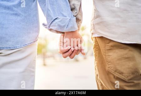 Bellissimo primo piano di una coppia caucasica irriconoscibile che tiene le mani all'esterno contro la luce del sole. Foto Stock