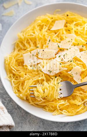 Spaghetti di zucca arrostiti e tagliati a pezzi serviti con olio d'oliva e parmigiano, idea di ricetta a basso contenuto di carboidrati, con una forchetta avvitata Foto Stock