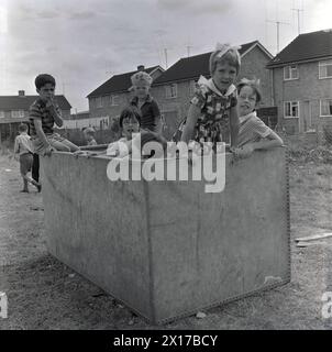 1964, storici, giovani fuori in un campo in una tenuta residenziale, che giocano in una grande cassa di compensato, probabilmente un vecchio container cargo, Inghilterra, Regno Unito. Foto Stock