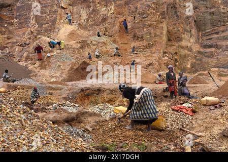 Un gruppo di uomini, donne e bambini, uno di loro tira fuori la lingua come se si prendesse in giro, scavò nella montagna per raccogliere pietre per costruire le loro case. Foto Stock
