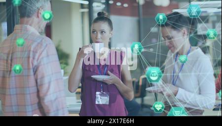 Immagine di globi di icone digitali su gruppi di colleghi diversi che discutono insieme in ufficio Foto Stock