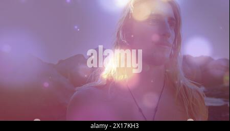 Immagine di macchie di luce sull'uomo caucasico in spiaggia Foto Stock