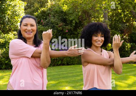 Donna birazziale matura e giovane donna birazziale esercizio in giardino a casa Foto Stock