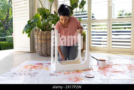 Donna birazziale matura che dipinge mobili a casa in un progetto di upcycling Foto Stock