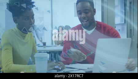 Due colleghi d'affari afroamericani stanno parlando e utilizzando un computer portatile nel loro ufficio Foto Stock