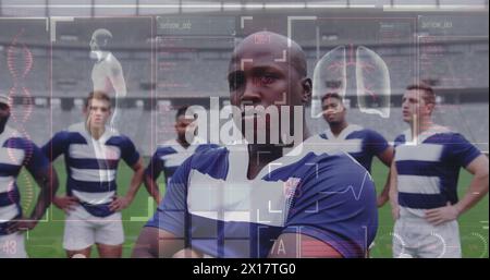 Immagine dei dati del corpo umano e delle statistiche sulla squadra di rugby maschile multietnica in piedi su un campo Foto Stock