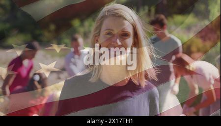 Immagine composita di bandiera americana su ritratto di volontaria caucasica che sorride nella foresta Foto Stock