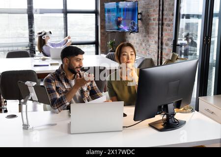 I professionisti asiatici maschi e femmine lavorano nei computer di un moderno ufficio commerciale Foto Stock