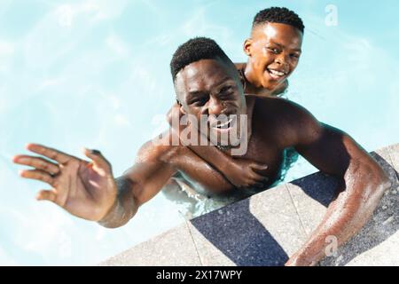 Padre e figlio afroamericani che si godono la piscina a casa Foto Stock