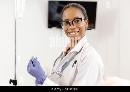 Un medico donna che indossa un cappotto bianco e guanti blu, pronto ad assistere i pazienti in un ambiente medico. Foto Stock