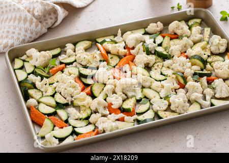 Varietà di verdure su una teglia pronta per essere arrostita con erbe e spezie fresche, cavolfiore e carote Foto Stock