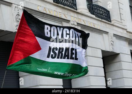 Londra, Regno Unito. 15 aprile 2024. Una bandiera palestinese che dichiara "boicottaggio di Israele” vola mentre i sostenitori palestinesi chiedono un cessate il fuoco immediato a Gaza e la dismissione da Israele in un raduno al di fuori del municipio di Camden, gestito dai laburisti, che si trova nella circoscrizione di Holborn e St Pancras del leader del partito laburista Sir Keir Starmer. Crediti: Ron Fassbender/Alamy Live News Foto Stock