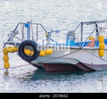 Barca da pesca ormeggiata con boe gialle e una gomma sulle calme acque blu del mare, in Corea del Sud Foto Stock