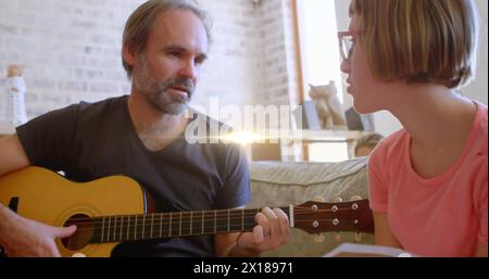 Immagine di una luce che lampeggia sul padre caucasico che suona la chitarra e canta a figlia Foto Stock