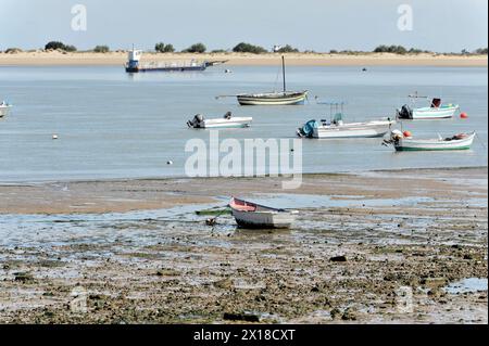 Guadalquivir, diverse piccole barche distese su sabbia asciutta a causa della bassa marea, sullo sfondo una nave più grande, l'Andalusia, Spagna Foto Stock