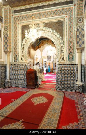 Fez, Un magnifico interno di una moschea con tappeti rossi e colonne a mosaico, Marocco settentrionale, Marocco Foto Stock