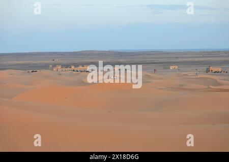 Vicino a Erfoud, crepuscolo su un piccolo insediamento circondato da dune di sabbia nel deserto, Medio Atlante, Marocco Foto Stock