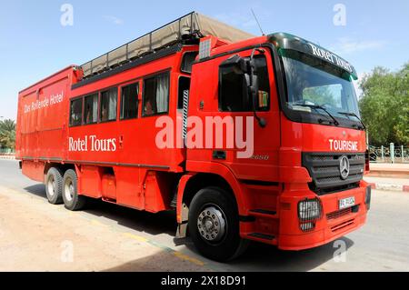 Rissani, pullman rosso a lunga percorrenza della Rotel Tours parcheggiato in un paesaggio desolato, Medio Atlante, Rissani, Marocco Foto Stock