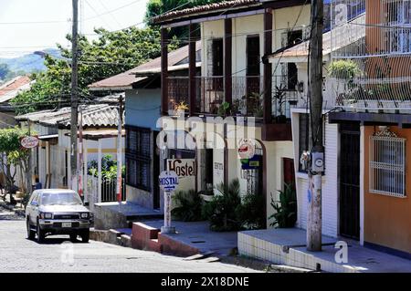 Leon, Nicaragua, vista della città con persone e veicoli di fronte a edifici tradizionali con balconi, America centrale, America centrale - Foto Stock