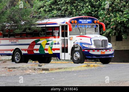 Sulla strada vicino a Rivas, Ometepe Island, Nicaragua, autobus cittadino parcheggiato colorato circondato da alberi su un tranquillo tratto di strada, Central America, Central Foto Stock