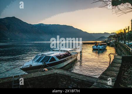 Piccola imbarcazione passeggeri che si sposta a Como sul Lago di Como - spostamento a zigzag . Piccolo motoscafo ancorato vicino alla costa sul lago di Como al tramonto e al darkis Foto Stock