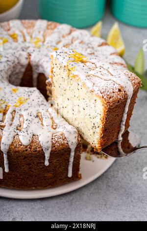 Torta con semi di papavero al limone, torta intera con una fetta tolata Foto Stock