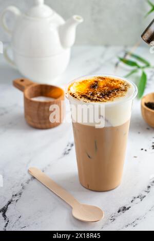 Crema di tè al latte brulee con schiuma fredda e zucchero caramellato in cima che viene tormentato con una torcia culinaria Foto Stock