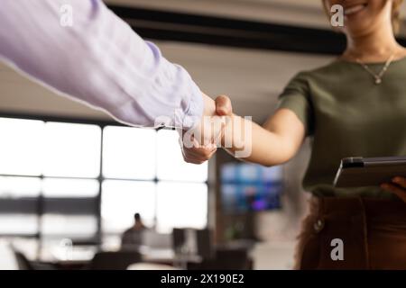 Un team eterogeneo stringe la mano, stringendo un accordo in un moderno ufficio aziendale Foto Stock