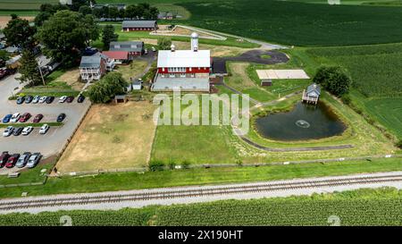 Ronks, Pennsylvania, 15 agosto 2023 - scattata dall'alto, questa foto raffigura un centro rurale con parcheggio adiacente, un incantevole laghetto e la vasta campagna che funge da sfondo. Foto Stock