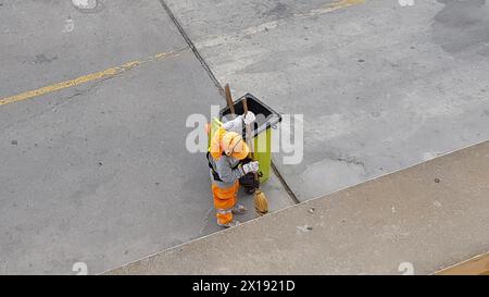 Vista dall'alto di un lavoratore che pulisce il marciapiede della strada spazzando via la spazzatura. Concetto di manutenzione pubblica Foto Stock