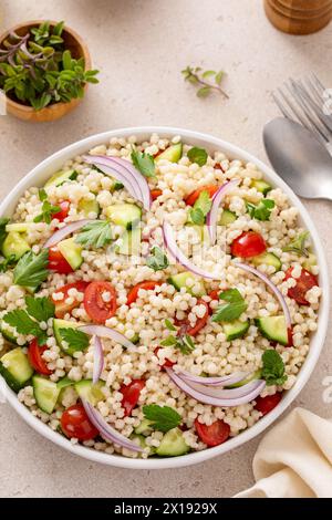 Insalata di couscous perla con verdure fresche ed erbe aromatiche in un recipiente da portata, idea di contorno sano Foto Stock