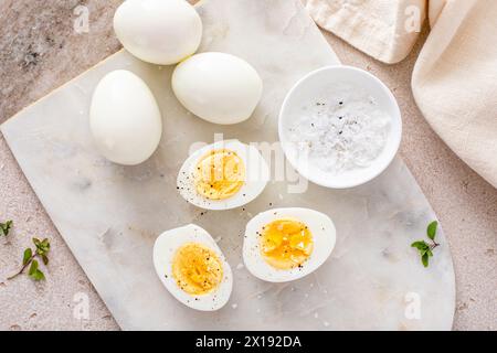 Uova sode sbucciate e tagliate a metà con sale e pepe Foto Stock