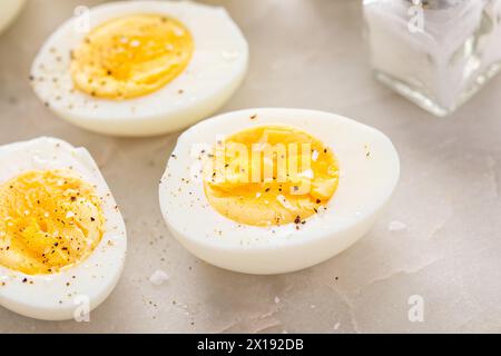 Uova sode sbucciate e tagliate a metà con sale e pepe Foto Stock