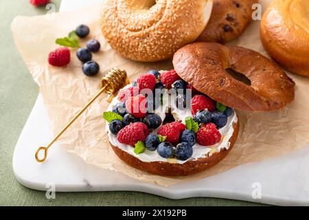 Bagel alla cannella con formaggio spalmabile, frutti di bosco freschi e miele per colazione Foto Stock