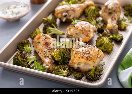 Cosce e cosce di pollo con teglia di broccoli cena o pranzo con aglio ed erbe arrostite e pronte da mangiare Foto Stock