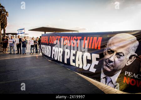 Tel Aviv, Israele. 15 aprile 2024. I manifestanti tengono uno striscione che invita il presidente degli Stati Uniti Joe Biden a non fidarsi del primo ministro israeliano Benjamin Netanyahu durante una manifestazione. Israele ha promesso di "determinare un prezzo” dall'Iran dopo un attacco senza precedenti su larga scala con drone e missili nel fine settimana che ha intensificato le tensioni regionali innescate dalla guerra a Gaza. Credito: SOPA Images Limited/Alamy Live News Foto Stock