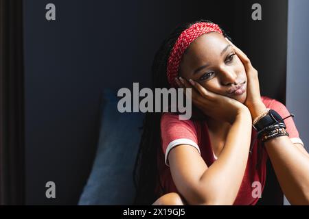 Giovane donna afroamericana seduta, che guarda premurosa a casa con spazio per le copie Foto Stock