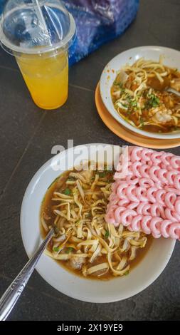 Questa deliziosa zuppa di spaghetti è servita con cracker rosa, solitamente chiamati mie Kocok Bandung, un tipico piatto culinario di Bandung. Foto Stock