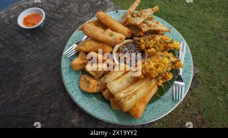 Vari cibi fritti serviti su piatti famosi in Indonesia, come il bakwan di mais, il mendoan, la banana fritta, la cassava fritta e il tofu fritto Foto Stock