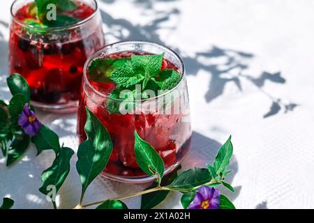 Rinfrescante bevanda estiva con frutti di bosco. Cocktail o mocktail con frutti di bosco stagionali maturi e menta. Bevanda disintossicante. Bevanda dissetante ghiacciata alla frutta. Foto Stock