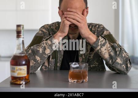 Concetto militare di abuso di droghe e alcool. Primo piano di soldato con whisky e pillole per trattare i suoi sintomi PTSD. Foto Stock