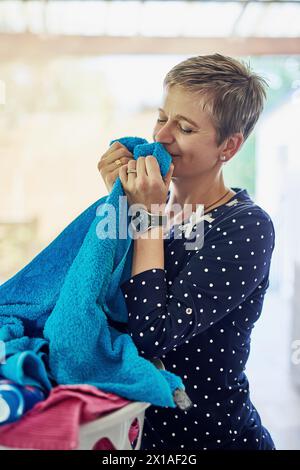 Lavatrice, pulita e donna puzzava un asciugamano dopo il rinfresco, i lavori domestici e il materiale per il lavaggio al mattino. Lavori domestici, pulizie e pulizie o donne Foto Stock