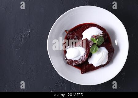 Gustoso vino rosso pere in camicia, menta e gelato sul tavolo nero, vista dall'alto. Spazio per il testo Foto Stock