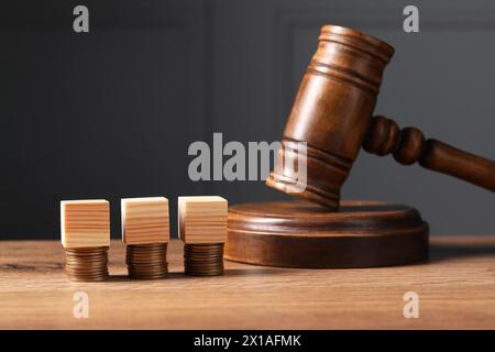 Legge fiscale. Cubi di legno vuoti, monete impilate e martelletto sul tavolo Foto Stock
