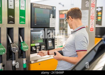 L'uomo paga il carburante con una carta di credito al terminal della stazione di servizio self-service in Europa Foto Stock