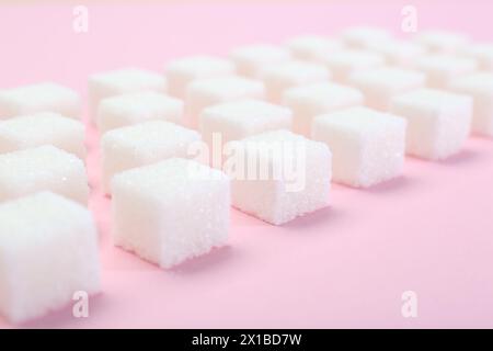 Cubetti di zucchero bianchi su sfondo rosa, primo piano Foto Stock
