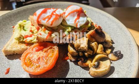 Uova con avocado, pomodoro, funghi e salsa al peperoncino servite per colazione in hotel. Foto Stock