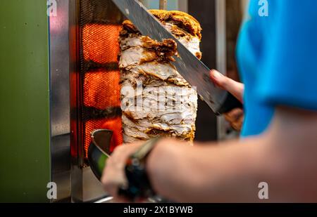 Uomo che taglia carne succosa con lo shawarma. Foto Stock
