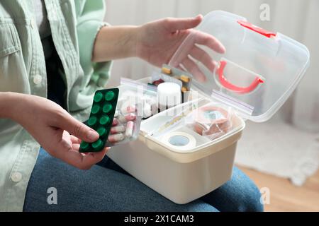 Donna che mette pillole nel kit di pronto soccorso al chiuso, primo piano Foto Stock